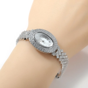 Gros plan d'une montre quartz ovale argentée avec lunette sertie de zircons