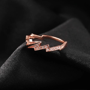 Macro shot of rose gold lightning ring with pavé-set zircons on black silk fabric