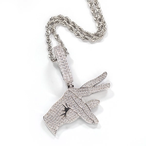 Macro detail of hip hop gesture pendant with white zircons and rope chain necklace