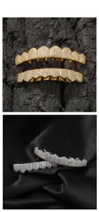 Detail view of gold and silver hip hop grillz with iced-out zircon fangs on black silk