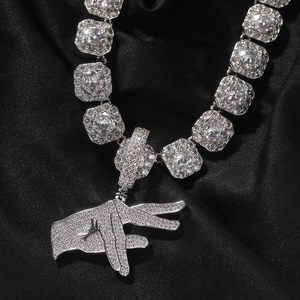 Detail of hip hop iced-out hand gesture pendant with cubic zirconia links on black silk