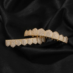 Detailed macro shot of gold-plated hip-hop grillz with white cubic zirconia stones on black silk