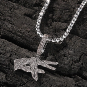 Close-up of hip hop silver pendant with cubic zirconia and tennis chain over dark background