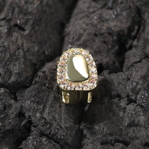 Macro shot of single gold-plated hip hop tooth grillz with cubic zirconia stones