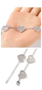 Dettaglio del bracciale con ciondoli a cuore con zirconi micro-pavé e chiusura a moschettone