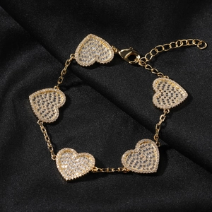 Dettaglio di cinque ciondoli a cuore placcati in oro con pavé di zirconi bianchi