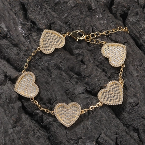 Dettaglio macro del bracciale a cuore dorato con cinque ciondoli in zircone micro-pavé