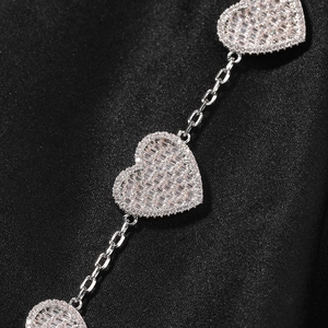 Dettaglio macro del ciondolo a cuore con diamanti baguette e pavé tondo in argento lucido