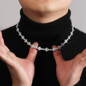 Close-up of sparkling silver clover tennis necklace worn on a black turtleneck sweater