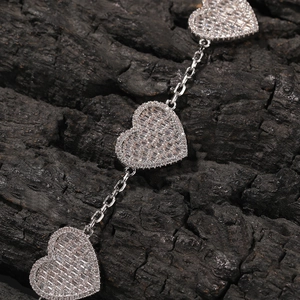 Vista macro di un bracciale a maglie a cuore con zirconi pavé e finitura argento