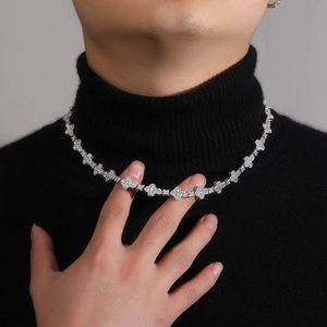 Detailed close-up of 10mm iced out cross flower necklace on a black turtleneck sweater
