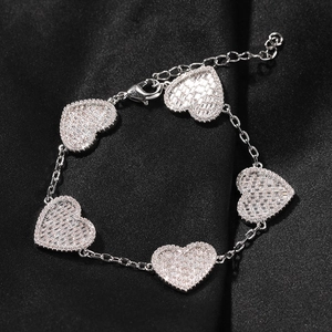 Dettaglio macro di cinque ciondoli a cuore in argento con pavé di zirconi su un bracciale