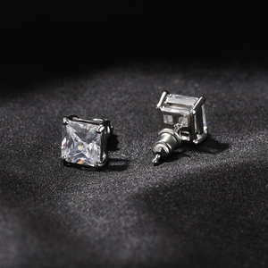 Détail de boucles d'oreilles carrées en argent serties de zircone sur tissu noir texturé