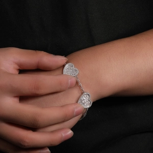 Dettaglio di un bracciale in argento con cuori di zirconi sul polso di una donna