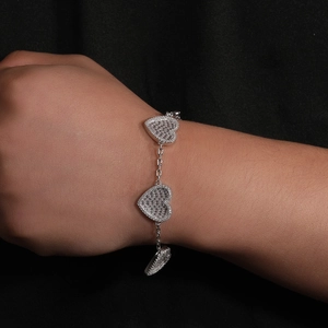 Dettaglio dei ciondoli a cuore con micro zirconi su un bracciale a maglie d'argento