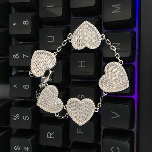 Dettaglio del bracciale a cuore in argento con pietre di zircone su sfondo scuro