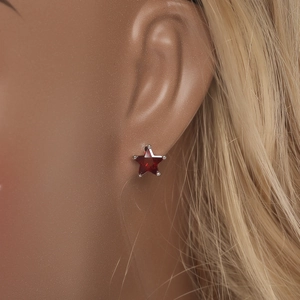 Gros plan d'une boucle d'oreille étoile en zircon rouge sur modèle avec griffes argentées