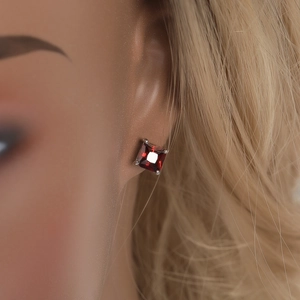 Vue latérale macro d'une boucle d'oreille en zircon rouge carré avec monture à griffes