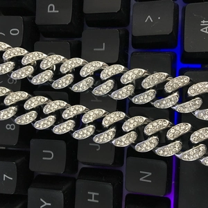 Gros plan d'une chaîne Cuban Link argentée de 12 mm avec strass sur un clavier