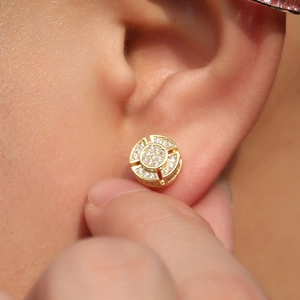 Macro shot of hip hop gold stud earring with round hub design and CZ stones on ear