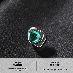 Macro view of a polished copper tooth grill with a faceted green heart-shaped gemstone