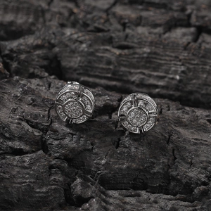 Macro shot of silver-tone hip hop stud earrings with pave-set zircon on black wood