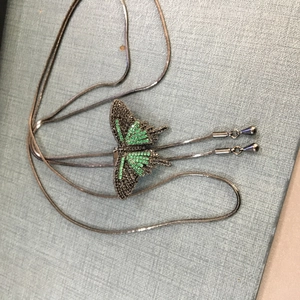 Nahaufnahme von Schmetterlingsanhänger mit grünen Zirkonen an einer Silberkette