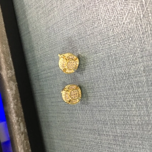 Detailed macro view of gold-plated iced out round stud earrings with pave cubic zirconia