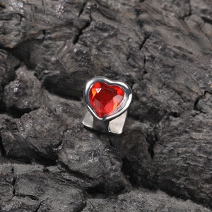Chic silver-tone ring with a large red heart-shaped gemstone on dark textured surface