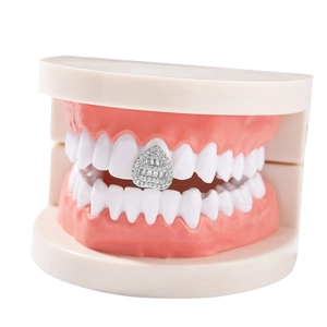 Macro shot of a silver heart-shaped single tooth grillz with white zircon inlay on dental mold
