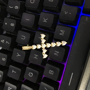 Gros plan du pendentif croix dorée serti de zircons en cœur sur un clavier