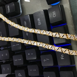 Détail macro d'une chaîne tennis dorée avec zircons triangulaires sur clavier