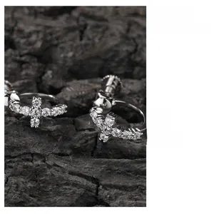 Détail de boucles d'oreilles créoles argentées avec pendentif croix et pierres de zircon 5A