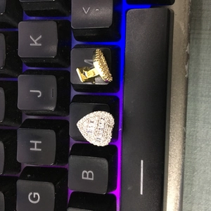 Close-up of heart-shaped gold and silver grillz with zircon stones on a dark background
