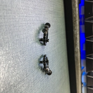 Vue macro de boucles d'oreilles croix noires serties de micro-zircons noirs brillants