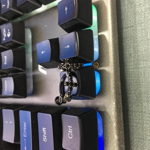 Gros plan d'un clou d'oreille croix gothique noire avec zircons sur clavier mécanique