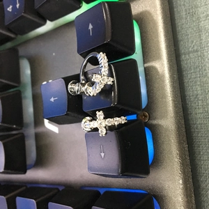Gros plan de boucles d'oreilles croix en argent avec pierres étincelantes sur clavier