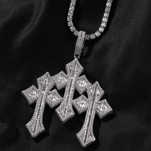 Detailed close-up of iced-out triple cross pendant with baguette-cut stones on tennis chain