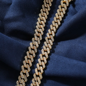Close-up of golden Cuban link necklace with white rhinestones on blue velvet background