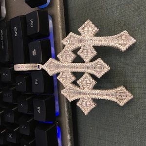Macro detail of iced out triple cross pendant with baguette and round cut stones