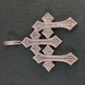 Macro shot of triple layered cross pendant with square cut and round white cubic zirconia