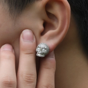 Gros plan d'un clou d'oreille tête de mort hip hop serti de zircons sur l'oreille