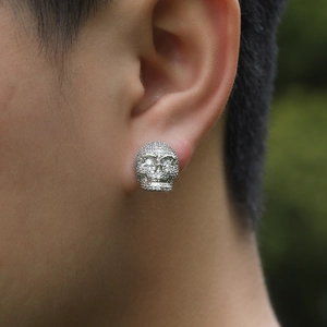 Gros plan d'une boucle d'oreille crâne hip-hop en argent sertie de zircons sur un homme