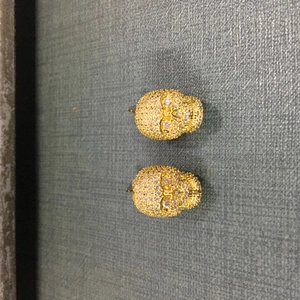Gros plan de boucles d'oreilles tête de mort dorées serties de zircons blancs