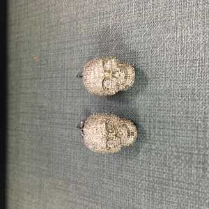 Détail macro de boucles d'oreilles tête de mort en argent serties de zircons blancs