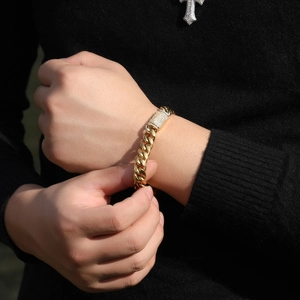Gros plan d'un bracelet gourmette doré avec fermoir boîte serti de diamants sur fond noir