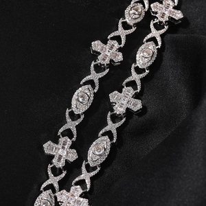 Macro detail of iced-out cross and eye link necklace on luxury black silk background