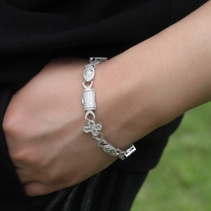 Close-up of iced-out hip hop bracelet with evil eye and cross charms on male wrist