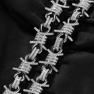 Macro shot of silver hip hop thorn necklace with sparkling diamonds on black silk