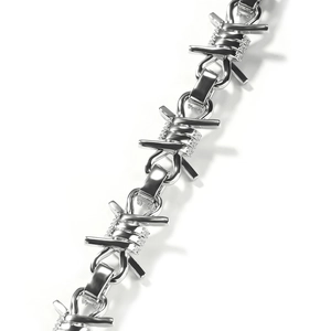 Macro view of hip hop thorn necklace links featuring polished silver and pavé diamonds